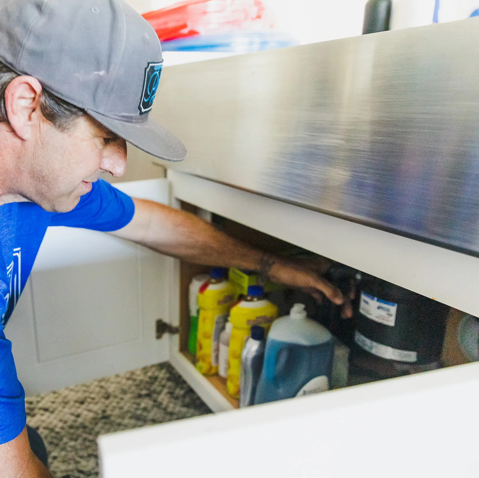 Phend Plumbing technician servicing a garbage disposal under a kitchen sink in an East Valley home