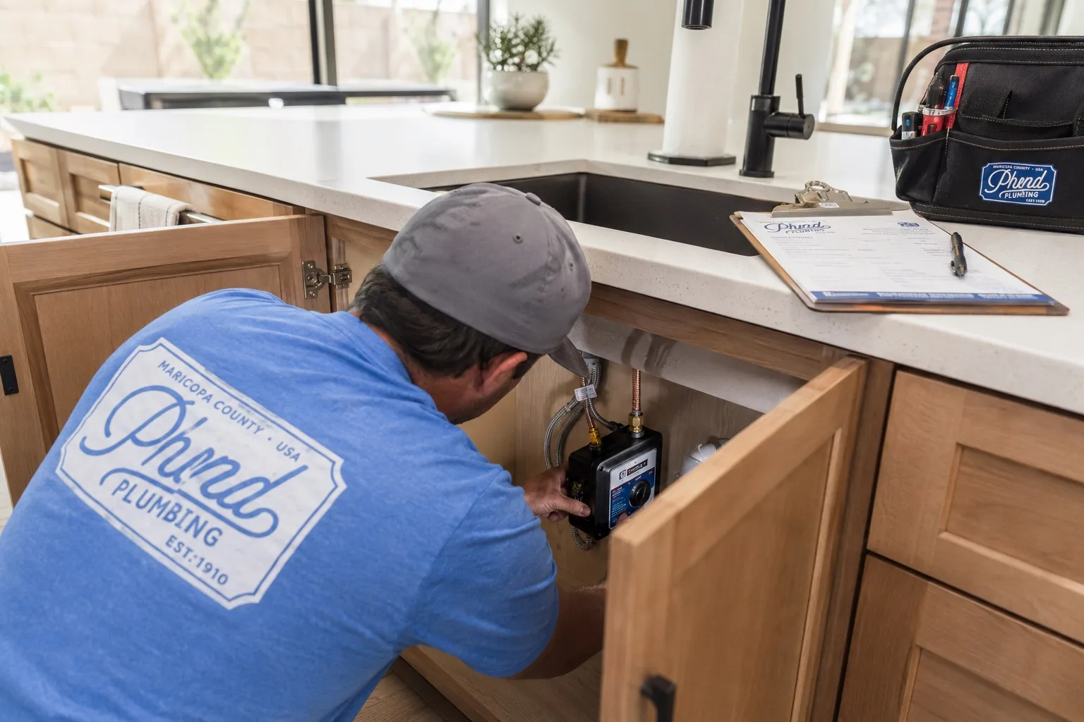 Phend Plumbing technician installing an under-sink instant hot water unit in a modern East Valley kitchen